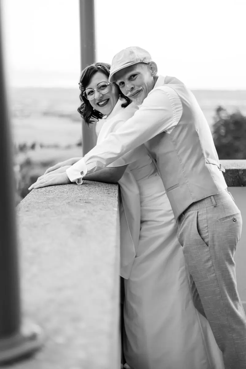 Moment Intime sur un Balcon à Grenoble - Laurent Pannetier Photographe Les mariés partageant un moment complice sur un balcon avec vue panoramique à Grenoble, capturés par Laurent Pannetier, photographe de mariage.