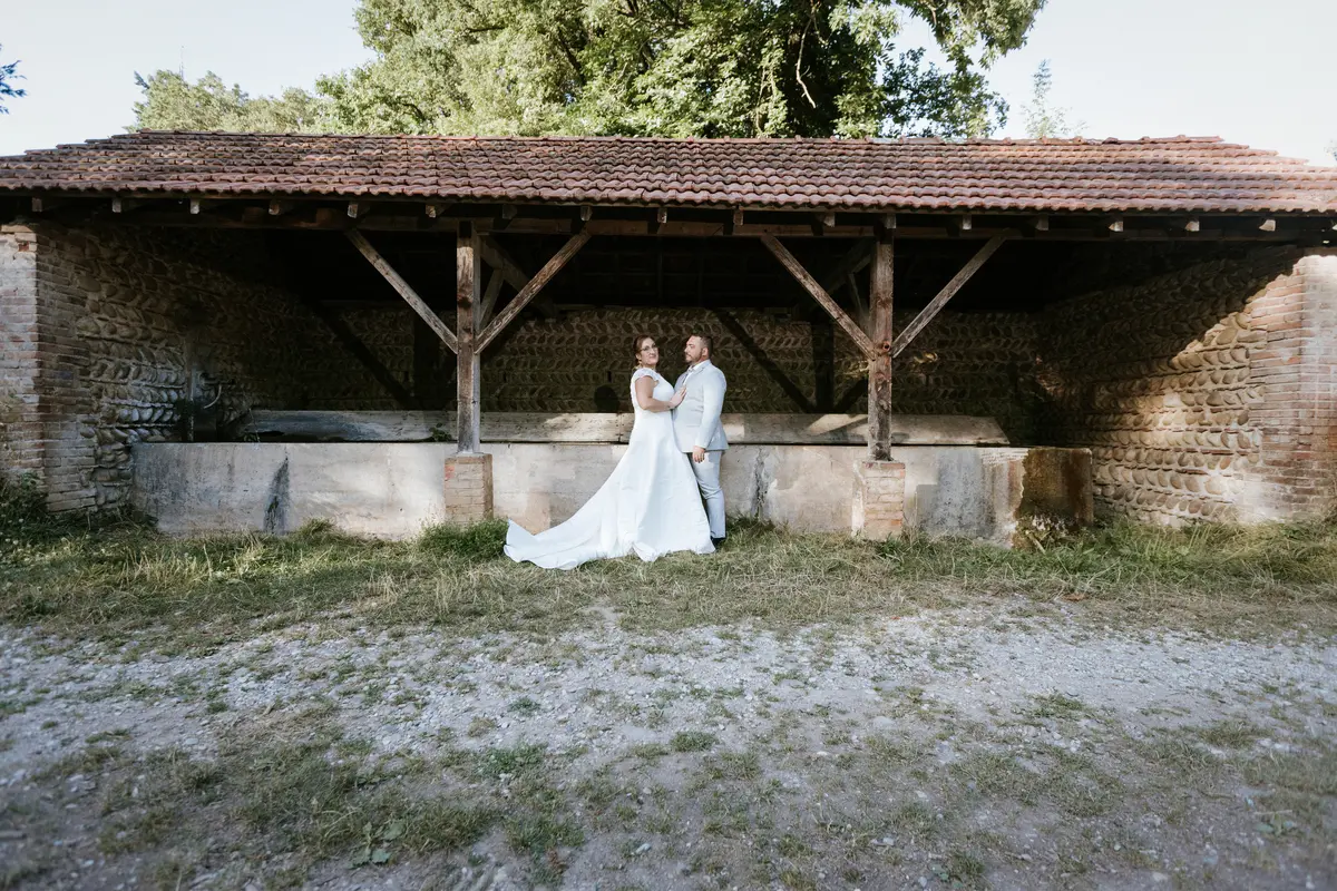 Couple de mariés posant devant un lavoir en pierre à Bourgoin-Jallieu, capturé par Laurent Pannetier, photographe professionnel.